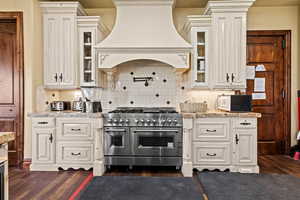 Kitchen featuring dark wood-type flooring, white microwave, custom range hood, and range with two ovens
