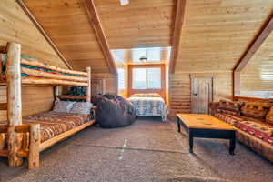 Carpeted bedroom featuring wooden walls, vaulted ceiling with beams, and wood ceiling