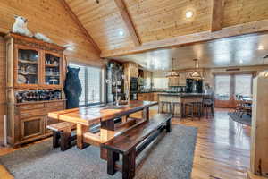 Dining room with light wood-type flooring, recessed lighting, wooden walls, wood ceiling, and vaulted ceiling with beams