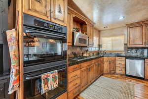 Kitchen with a sink, light wood-type flooring, appliances with stainless steel finishes, recessed lighting, and backsplash