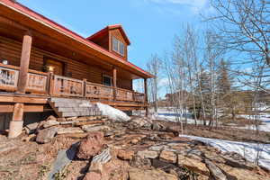 View of snow covered exterior featuring a porch and stairway