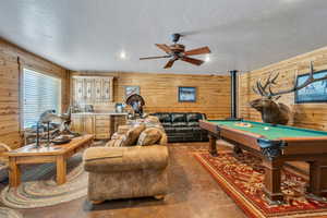 Playroom with wood walls, concrete floors, billiards, and ceiling fan