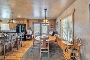 Dining room featuring a textured wall, recessed lighting, light wood-style floors, and a healthy amount of sunlight