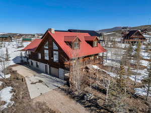 Snow covered property featuring a mountain view, driveway, metal roof, and a garage