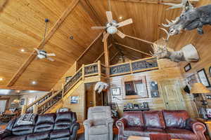 Living room with wooden ceiling, wooden walls, a ceiling fan, and stairway