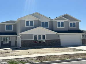 Craftsman-style house with an attached garage, board and batten siding, driveway, and brick siding