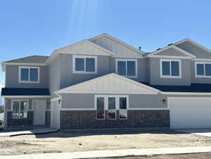View of front of house featuring brick siding, an attached garage, board and batten siding, and concrete driveway