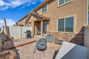Rear view of house with fence, cooling unit, a patio, and stucco siding