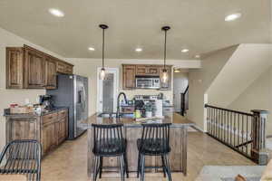 Kitchen with a sink, a breakfast bar, a textured ceiling, recessed lighting, and stainless steel appliances