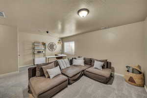 Living area with visible vents, baseboards, carpet, and a textured ceiling