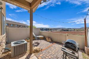 View of patio with a mountain view, grilling area, a fenced backyard, and cooling unit