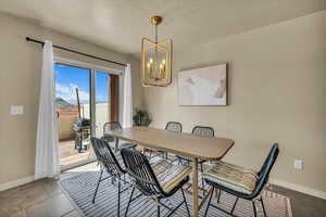 Dining room featuring a notable chandelier, baseboards, and a textured ceiling