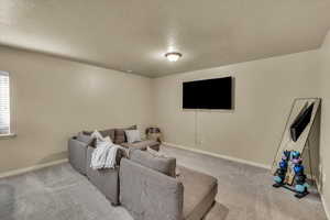 Living area featuring a textured ceiling, carpet flooring, and baseboards