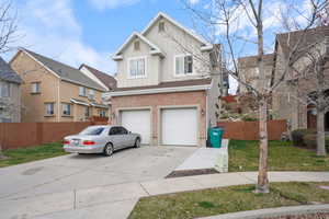 Traditional-style home with board and batten siding, fence, brick siding, an attached garage, and concrete driveway