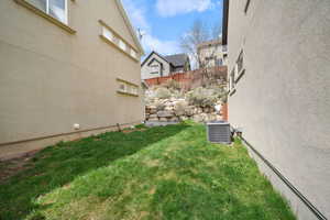 View of yard with central AC and fence