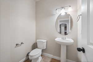 Half bath featuring toilet, baseboards, and tile patterned flooring