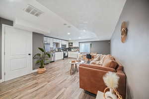 Living area featuring recessed lighting, light wood finished floors, visible vents, and baseboards