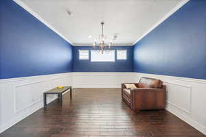 Unfurnished room featuring a chandelier, crown molding, dark wood-style floors, and wainscoting