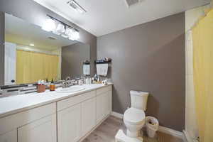 Full bathroom featuring toilet, wood finished floors, and visible vents