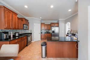 Kitchen with a peninsula, arched walkways, appliances with stainless steel finishes, a sink, and decorative backsplash