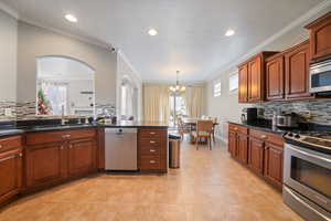 Kitchen with decorative backsplash, a sink, a notable chandelier, and stainless steel appliances