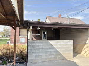 Doorway to property with brick siding, a porch, and central AC unit