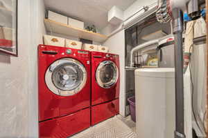 Laundry area featuring a textured wall, washing machine and dryer, and laundry area
