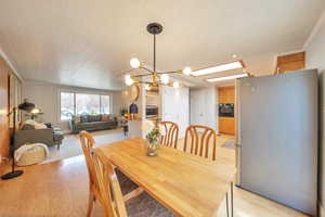 Dining space featuring light wood-type flooring, crown molding, a notable chandelier, and baseboards