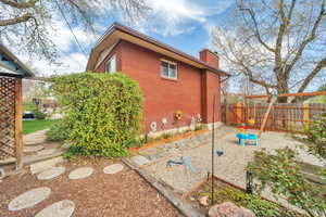 View of side of property featuring fence, brick siding, and a chimney