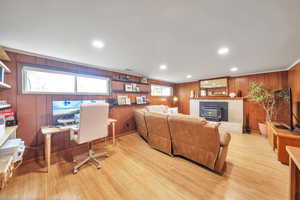 Living area with wood walls, a wood stove, light wood-style floors, and recessed lighting