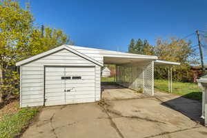 Garage with a detached garage, concrete driveway, and fence