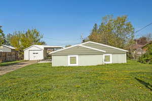 View of property exterior featuring a lawn, fence, and an outbuilding