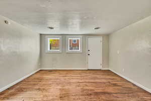 Unfurnished room featuring visible vents, baseboards, and wood finished floors
