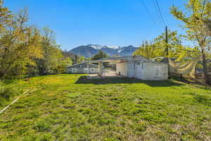 View of yard featuring fence, an outbuilding, a storage shed, and a mountain view