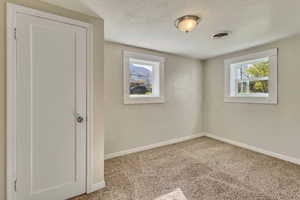 Carpeted empty room featuring visible vents and baseboards