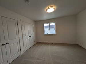 Unfurnished bedroom featuring visible vents, baseboards, carpet flooring, and a textured ceiling