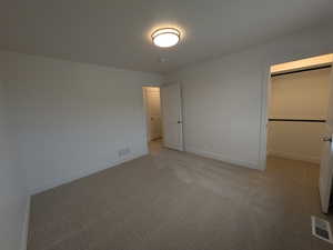 Unfurnished bedroom featuring light carpet, baseboards, and visible vents