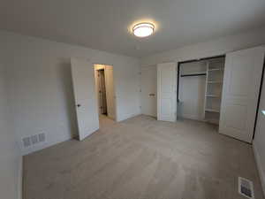 Unfurnished bedroom with visible vents, baseboards, and light carpet