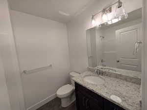Full bathroom featuring baseboards, toilet, a shower, vanity, and wood finished floors