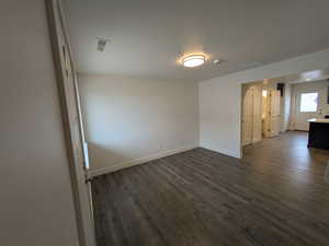 Unfurnished room with baseboards, a textured ceiling, and dark wood finished floors