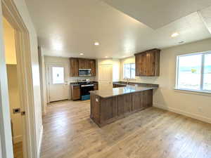 Kitchen featuring baseboards, electric range oven, a sink, a peninsula, and stainless steel microwave