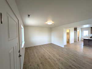 Empty room with baseboards, light wood-style flooring, a textured ceiling, and visible vents