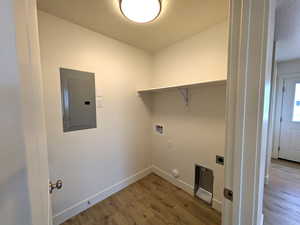 Laundry room with wood finished floors, hookup for a gas dryer, laundry area, and electric panel