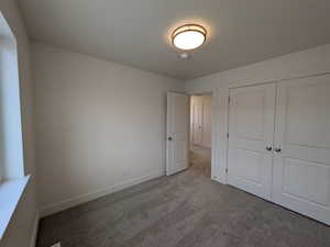 Unfurnished bedroom featuring a closet, carpet flooring, and baseboards