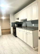 Kitchen featuring tasteful backsplash, electric range, marble finish floor, a sink, and baseboards