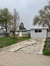 Exterior space featuring concrete driveway, fence, and a lawn