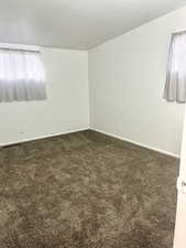 Spare room featuring dark carpet, baseboards, and visible vents