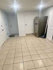 Kitchen with light tile patterned floors and freestanding refrigerator
