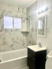 Full bathroom with a textured wall, shower / bath combination, vanity, and toilet