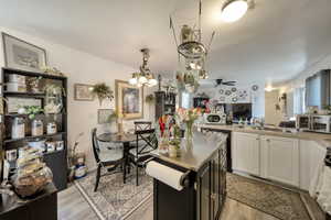 Kitchen featuring wood finished floors, a sink, ceiling fan, and white cabinetry